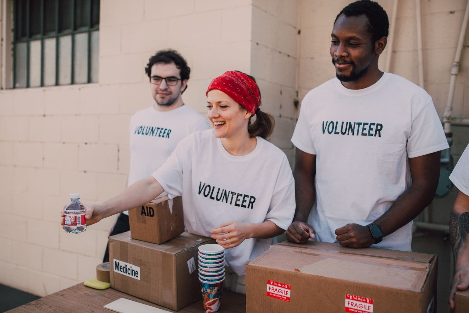 Volunteers laughing together at a community event supplies table